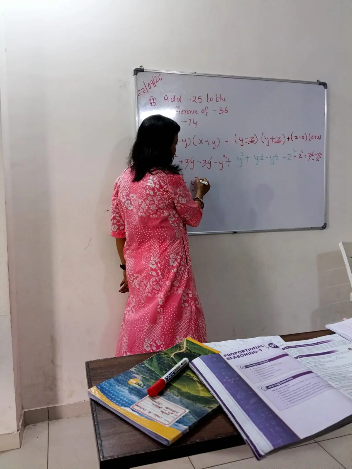 Teacher at the board with books on the desk